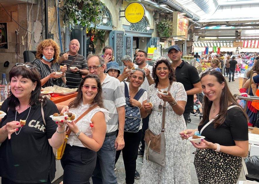 צילום של עושים שוק במחנה יהודה עם "ירושלים מחוץ לקופסה"